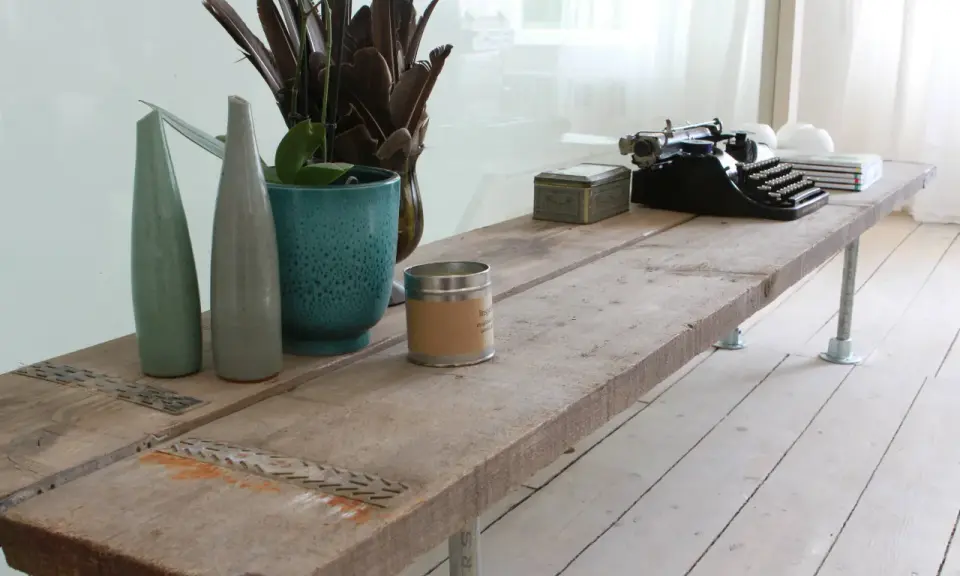 Une table basse rustique, idéale pour savoir que faire avec des vieilles planches de bois. Elle est décorée d'une machine à écrire vintage, de vases et d'une bougie.
