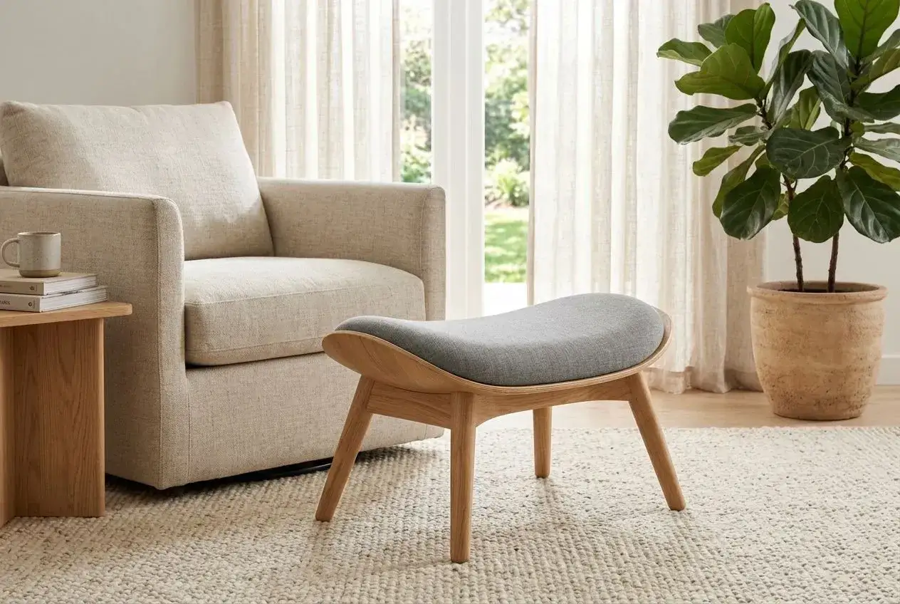 Un fauteuil confortable, un pouf design en bois et tissu gris, une plante verte et des rideaux clairs. Id&eacute;al pour un conseil d&eacute;coration int&eacute;rieur gratuit.
