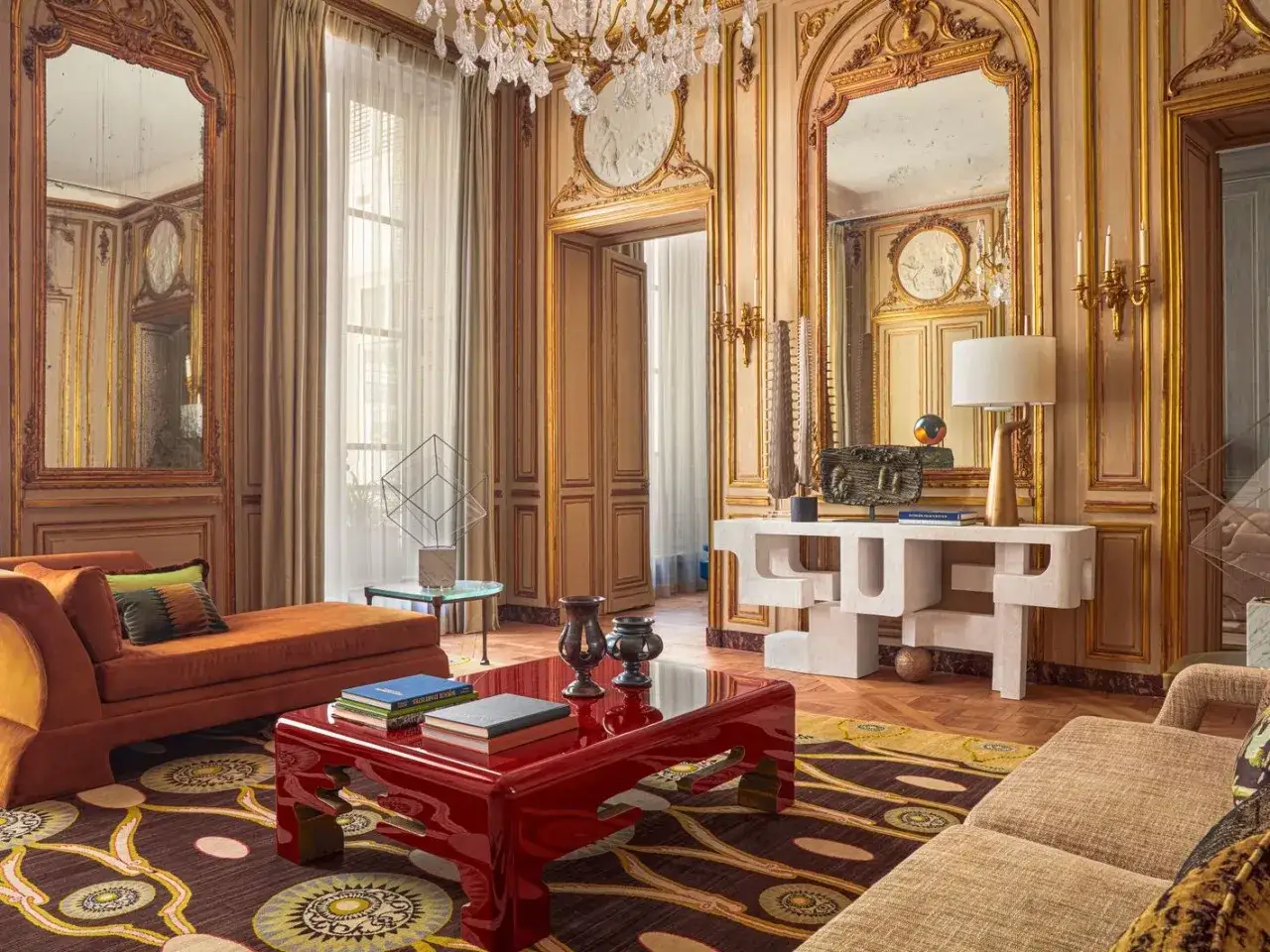 Salon luxueux avec canapé orange, table basse rouge, tapis graphique et console sculpturale. Une décoration appartement élégante et audacieuse.