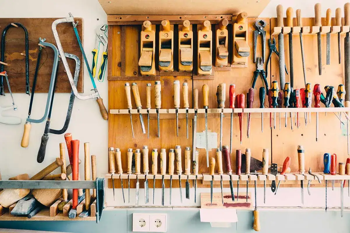 Un atelier bien rang&eacute;, pr&ecirc;t &agrave; construire un meuble de rangement. Des outils &agrave; bois, des scies, des ciseaux et des rabots sont organis&eacute;s sur un panneau mural.