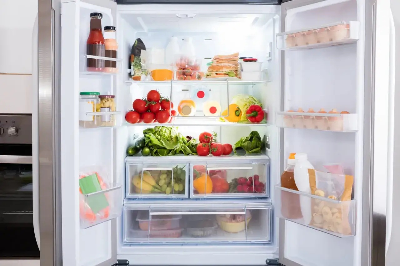 Comment ranger son frigo cong&eacute;lateur en bas : l&eacute;gumes, fruits, tomates, &oelig;ufs, bouteilles et sandwichs bien organis&eacute;s sur les &eacute;tag&egrave;res et dans les tiroirs.