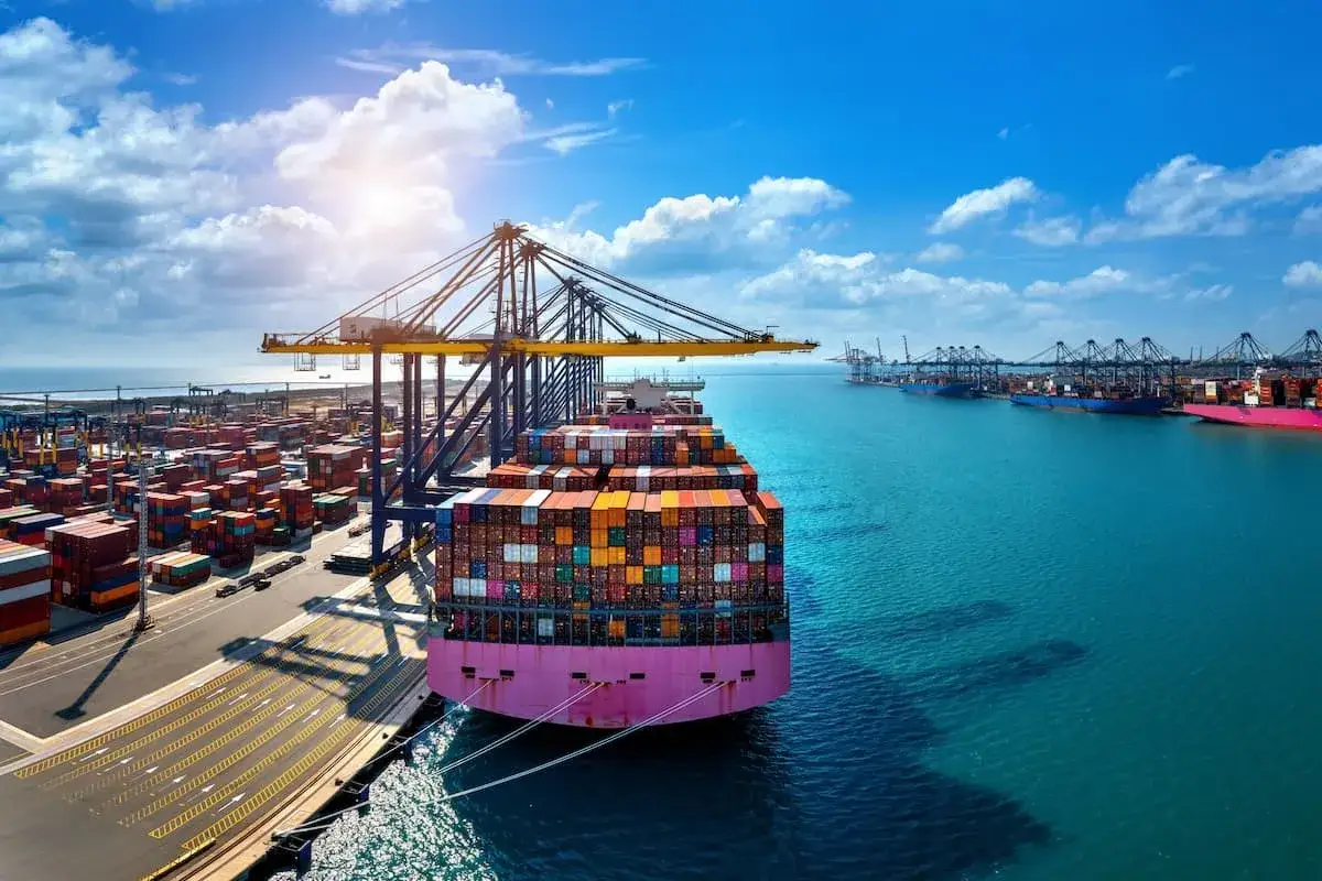 Un port maritime animé avec des grues chargeant des conteneurs sur un immense navire. Le tarif conteneur France Réunion est un facteur clé pour le commerce.
