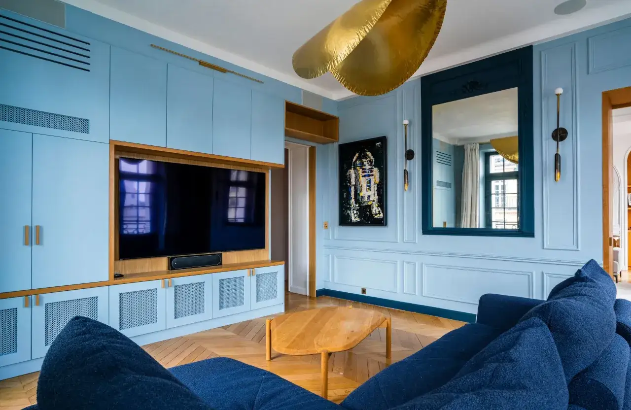 Salon bleu ciel avec mobilier sur mesure, tableau R2-D2 et canap&eacute; bleu marine. Un excellent conseil couleur peinture pour un int&eacute;rieur moderne.