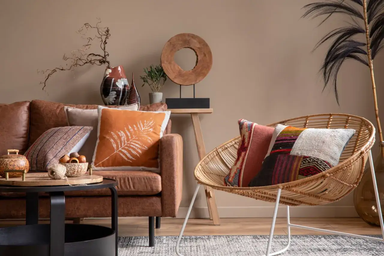 Salon chaleureux avec canap&eacute; en cuir marron, coussins color&eacute;s et fauteuil en rotin. Une belle idee deco interieur pour un espace cosy.