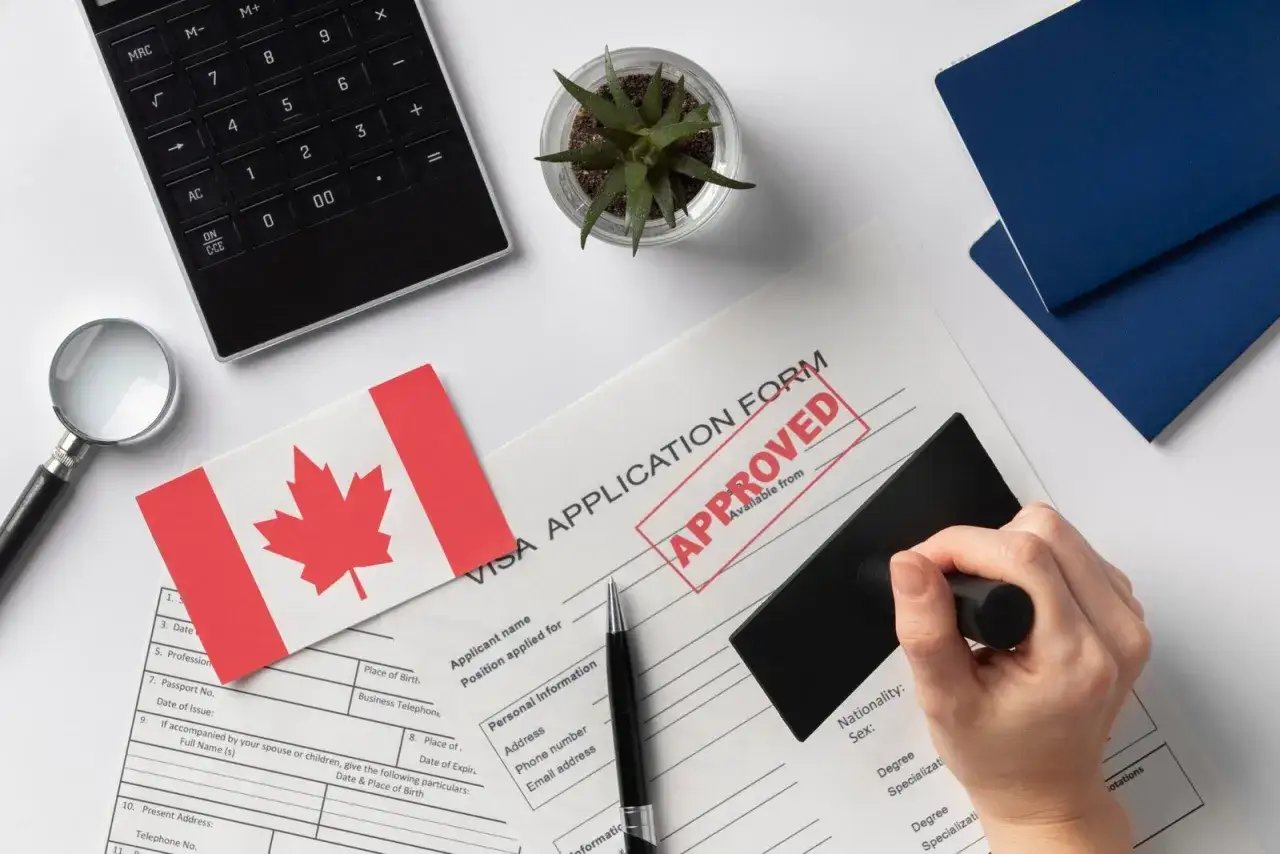 Formulaire de visa canadien approuv&eacute;, pr&ecirc;t pour un d&eacute;m&eacute;nagement France-Canada. Calculatrice, loupe et drapeau canadien.