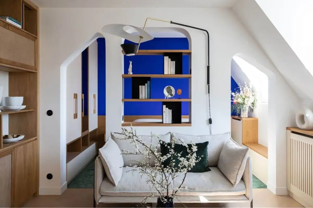 Salon moderne avec canap&eacute; clair, &eacute;tag&egrave;res en bois et murs d'un bleu klein et bleu majorelle saisissant.