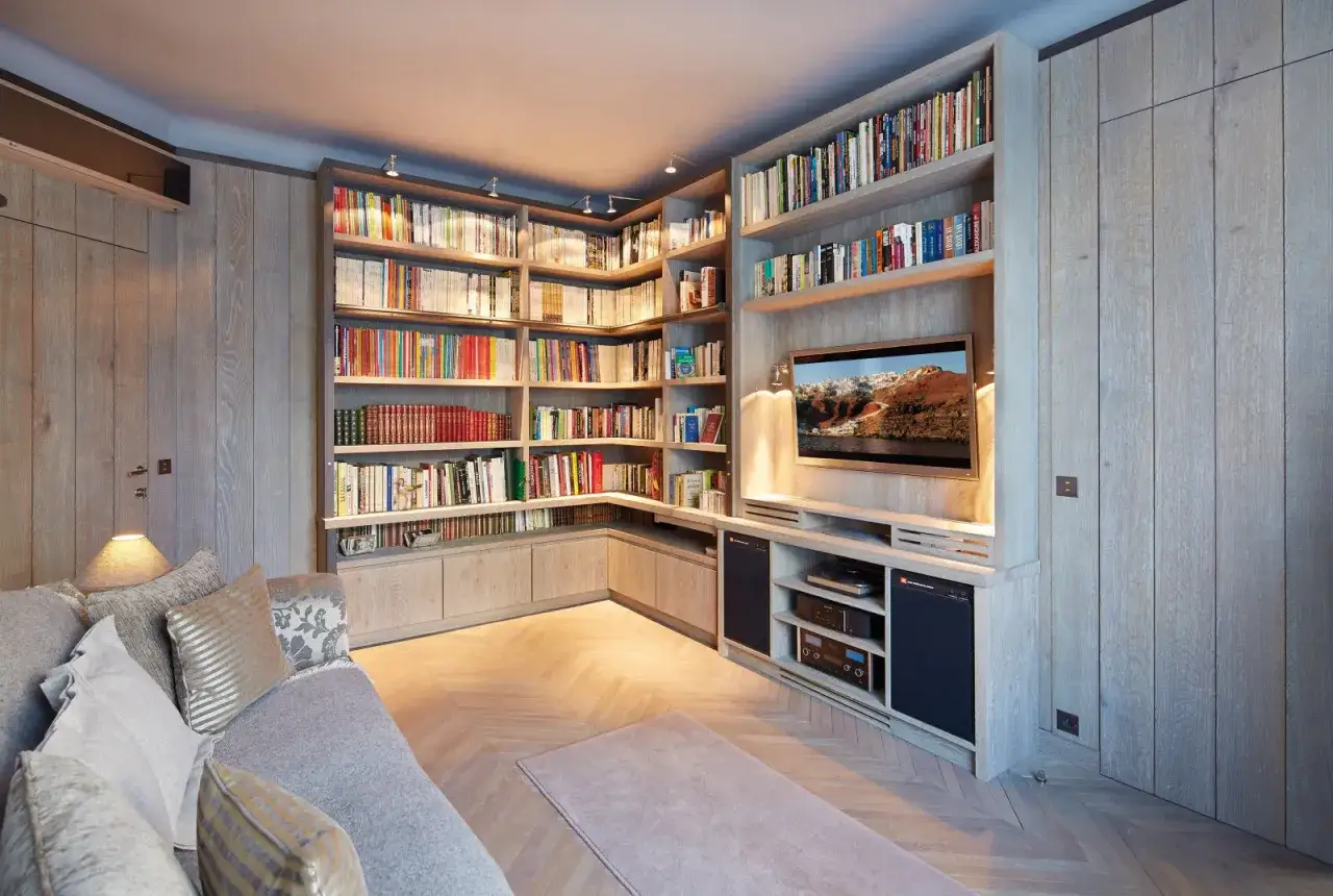 Un bel agencement biblioth&egrave;que en bois clair, avec une t&eacute;l&eacute;vision int&eacute;gr&eacute;e et un canap&eacute; confortable.