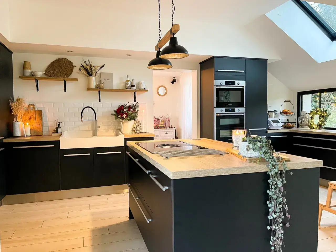 Cuisine moderne avec îlot central en bois clair et plan de travail noir. Une belle idee amenagement cuisine pour un espace fonctionnel et chaleureux.