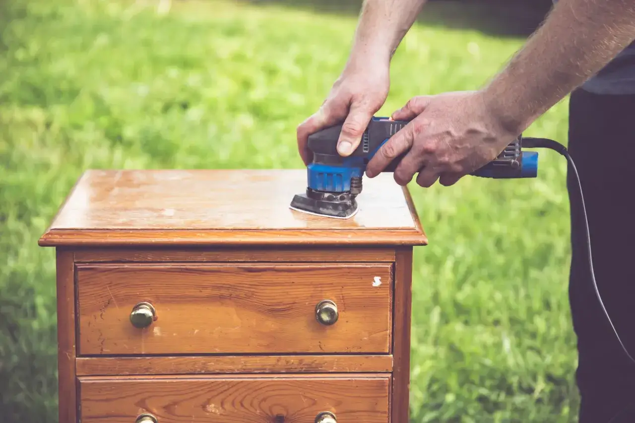 Homme pon&ccedil;ant un meuble en bois pour comment d&eacute;caper un meuble en bois fonc&eacute;. L'outil &eacute;lectrique enl&egrave;ve la vieille finition.
