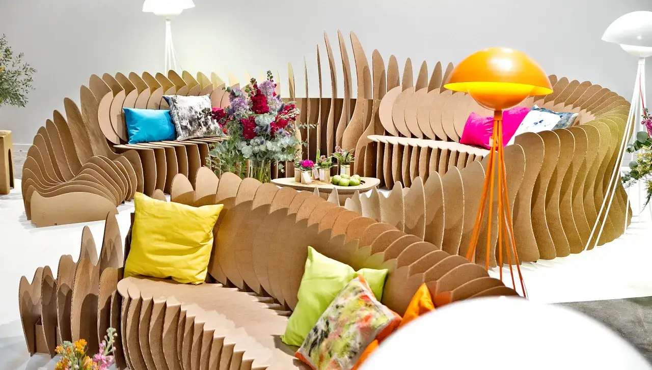 Salon moderne en carton ondul&eacute;, avec coussins color&eacute;s et lampe orange. Une d&eacute;co originale et &eacute;cologique.