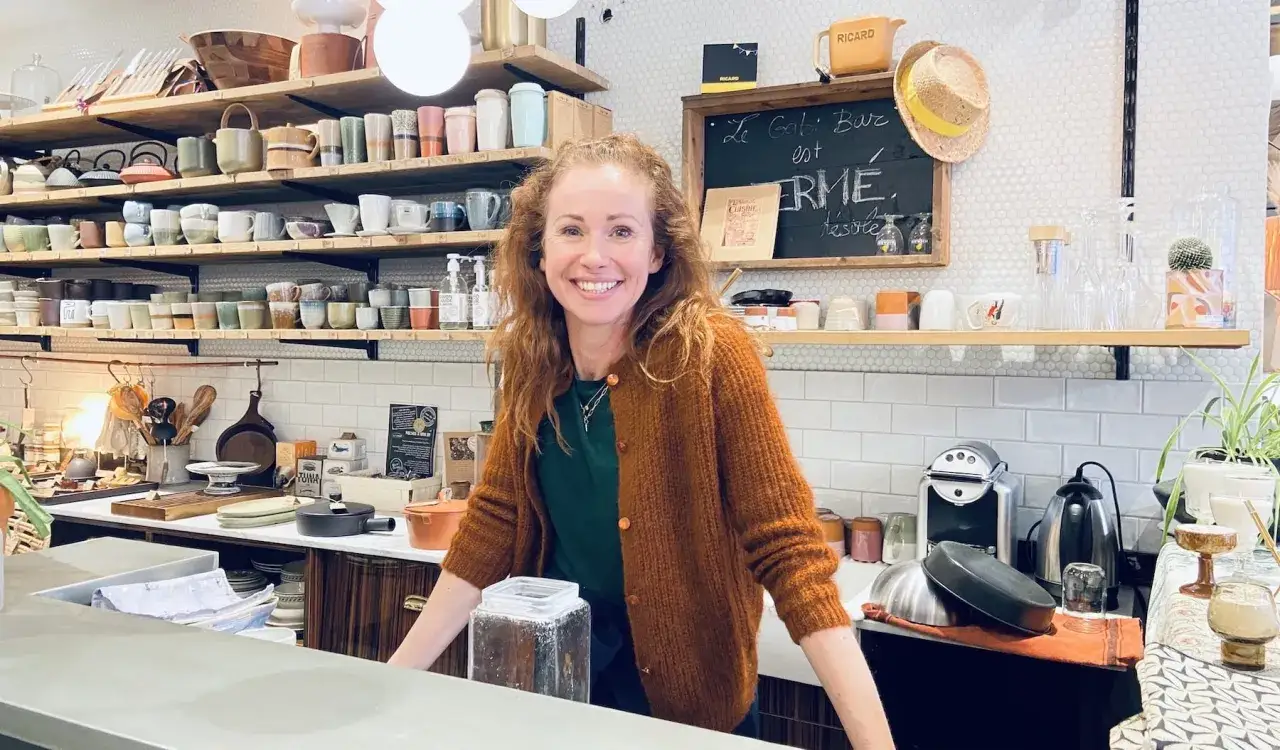 Sophie Ferjani, souriante, dans une boutique remplie d'objets de d&eacute;coration et de vaisselle.