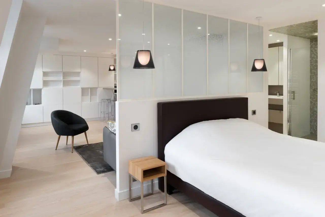 Un petit appartement pour femme seule, moderne et lumineux, avec un coin chambre s&eacute;par&eacute; par une paroi vitr&eacute;e.