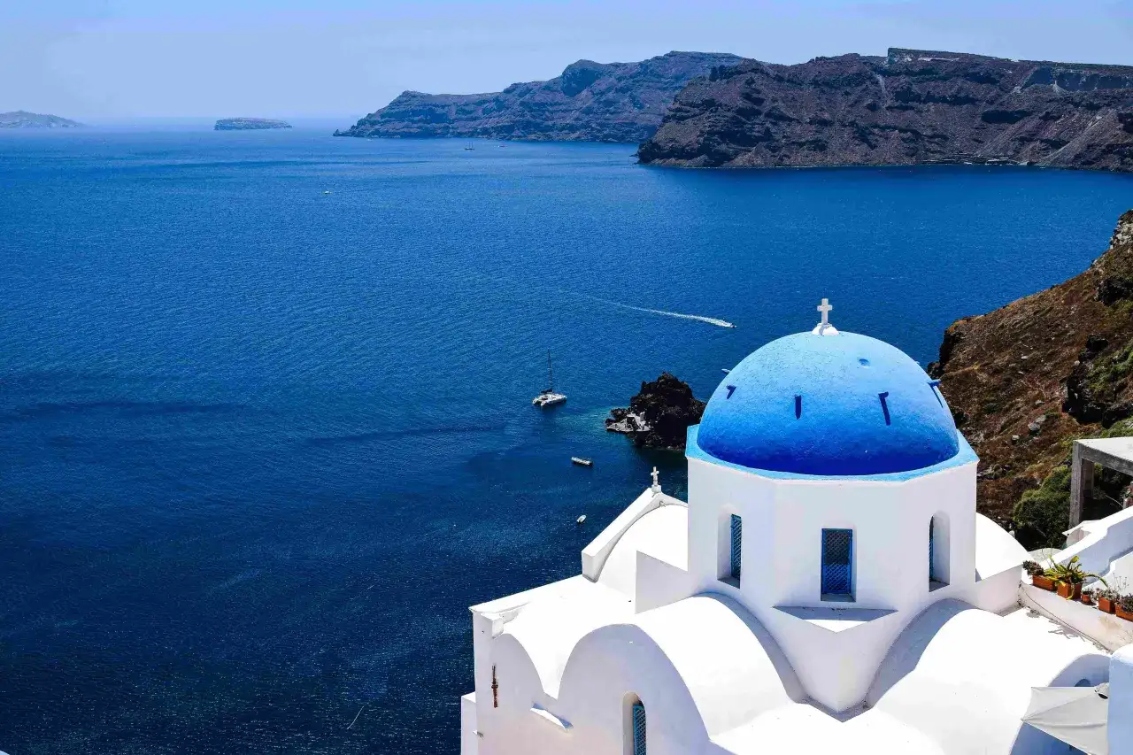 Vue d'une &eacute;glise typique maison grecque avec un d&ocirc;me bleu &eacute;clatant, surplombant la mer &Eacute;g&eacute;e bleue et les falaises rocheuses.