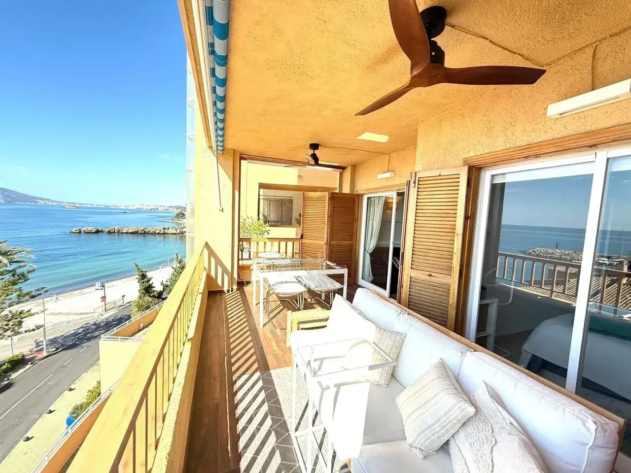 Balcon avec vue mer, parfait pour d&eacute;m&eacute;nager en Espagne et profiter du soleil. Canap&eacute; blanc, table et chaises pour des repas en plein air.