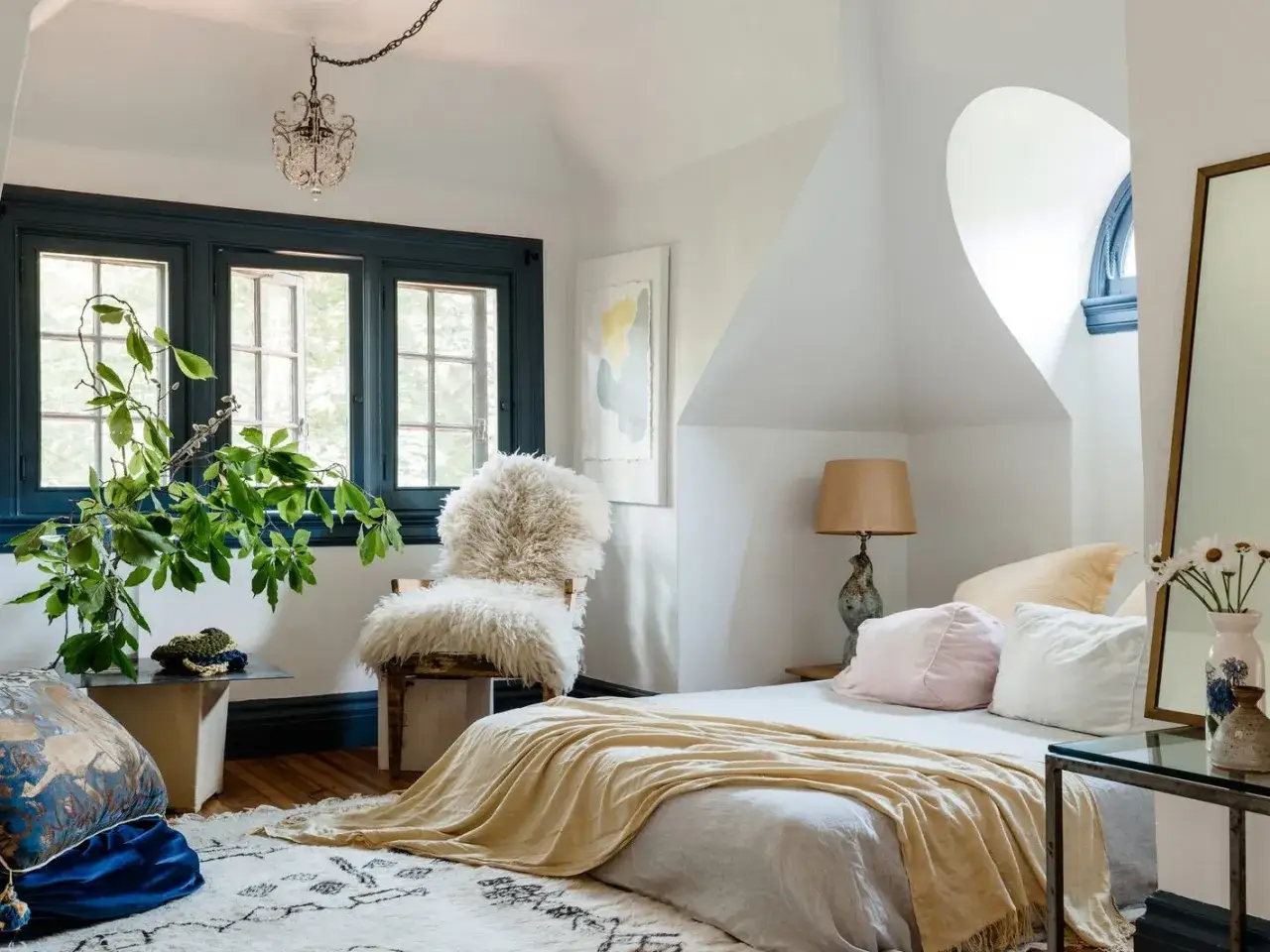 Chambre &agrave; coucher simple et moderne avec un fauteuil en fausse fourrure, un lit douillet et une plante luxuriante pr&egrave;s de la fen&ecirc;tre.