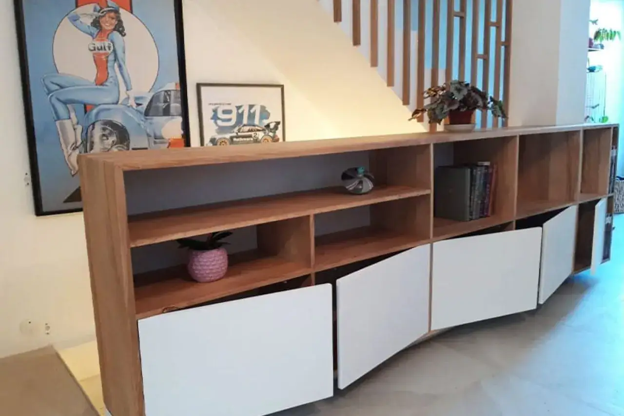 Meuble bas en bois, &oelig;uvre d'un menuisier &eacute;b&eacute;niste, avec portes blanches incurv&eacute;es et &eacute;tag&egrave;res ouvertes.