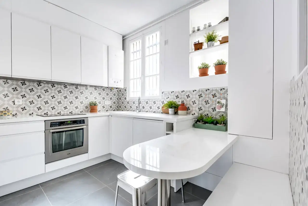 Cuisine moderne avec cr&eacute;dence blanche &agrave; motifs g&eacute;om&eacute;triques, plan de travail arrondi et &eacute;lectrom&eacute;nager int&eacute;gr&eacute;. Une belle id&eacute;e pour une cuisine blanche lumineuse.