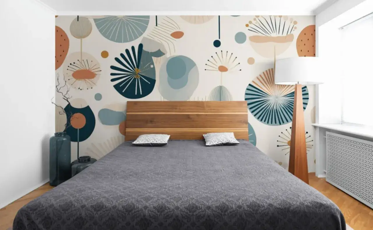 T&ecirc;te de lit en bois devant un mur orn&eacute; d'une peinture graphique abstraite aux formes organiques et aux couleurs douces.