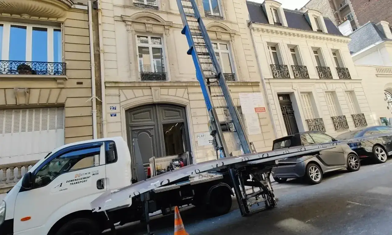 Camion de d&eacute;m&eacute;nagement avec monte-meubles devant un immeuble parisien. Une nouvelle aventure commence avec ce d&eacute;m&eacute;nagement &agrave; Paris.