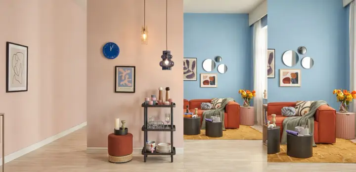 Salon aux murs bleu ciel et rose poudré, mobilier orange vif, tapis jaune moutarde et accents de **couleur pastel**.