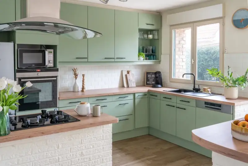 Cuisine vert d'eau et bois, avec des armoires douces, un plan de travail en bois chaleureux et des touches de blanc. Un espace invitant pour cuisiner et partager.