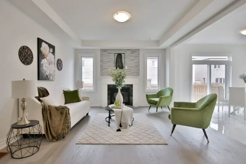 Salon moderne avec canapé blanc, fauteuils verts et cheminée. Idéal pour un conseil décoration intérieur gratuit.